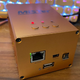 A photo of a MiSTer retro gaming box encased in a fancy gold aluminum case.